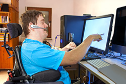 Image of a man in a wheelchair working on a computer