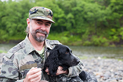 Smiling Veteran by the river holding a dog